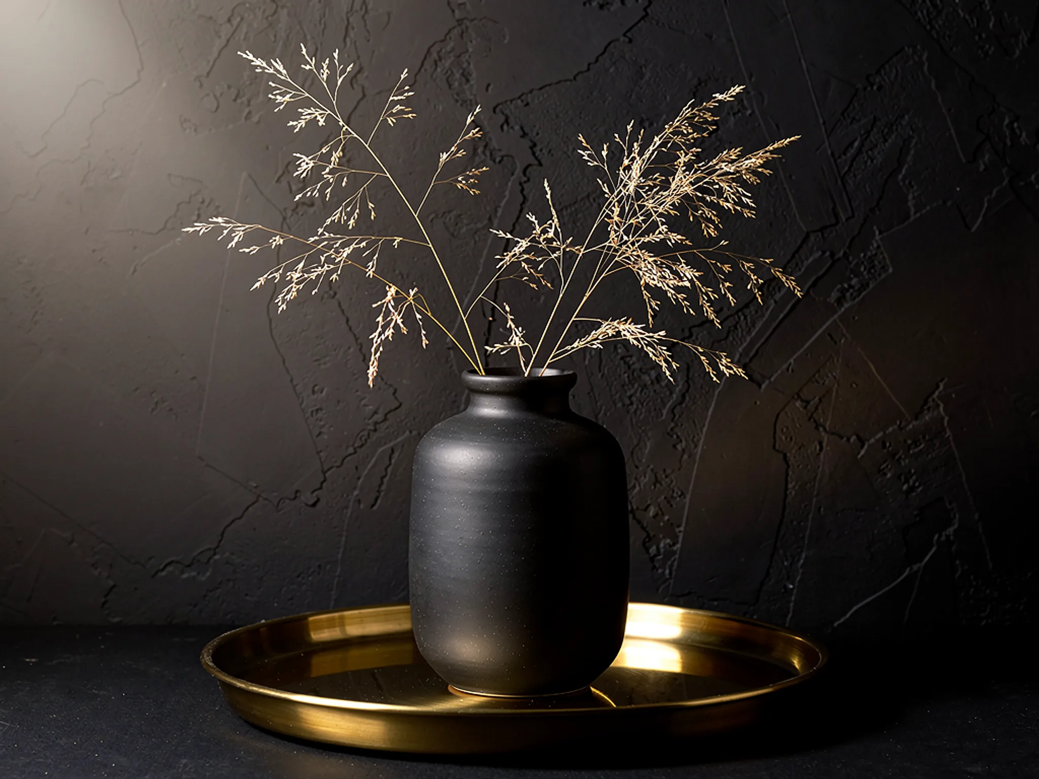 Stoneware Vase: A matte black vase with dried grass on a brass tray.